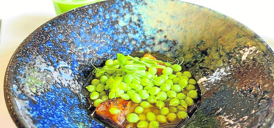 Delicadeza. Guisante lágrima de Eco Tierra Mojada con un jugo de manitas y oreja de cerdo crujiente, que se acompaña de un vaso con un caldo del propio guisante. 