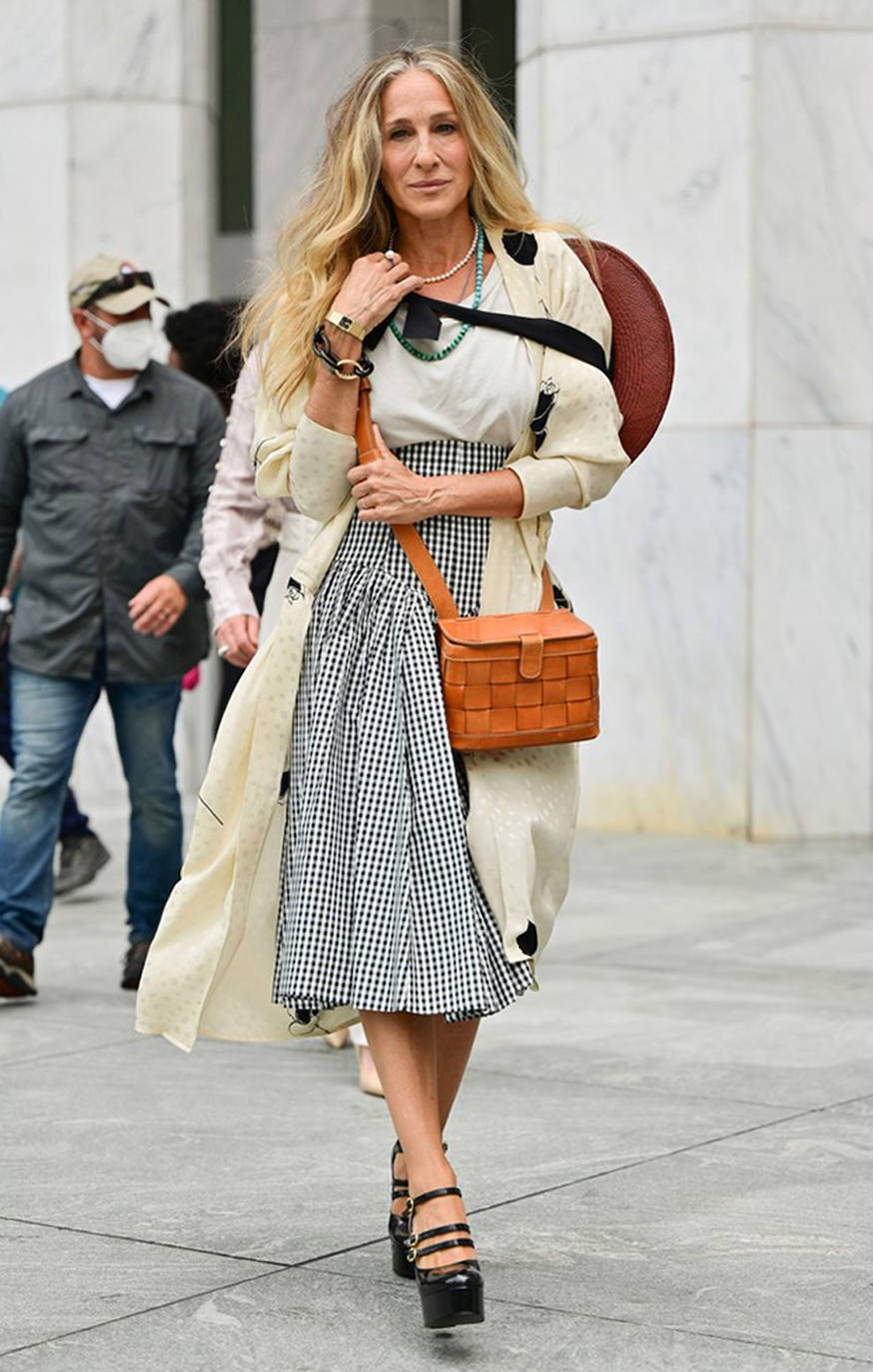 Aquí Carrie repite chaqueta en tono crudo, con un look de campesina de ciudad. Falda de cuadro vichy blanco y negro vintage de Norma Kamali de inspiración victoriana, que rompe con una camiseta básica. Bolso marón cruzado y maxisombrero. Agregó el zapato Mary Jane de tres hebillas 'Melody' de Celine de la colección Otoño / Invierno 2020 de la marca. A continuación, SJP se complementó con una pulsera de cadena Parts of 4 'Infinity' y un collar de cuerda de turquesa y malaquita de Fry Powers.