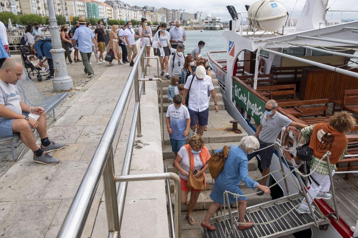 Grupos de vecinos y turistas, ayer, en el Paseo Marítimo de Santander, suben a una de las embarcaciones de Los Reginas. 