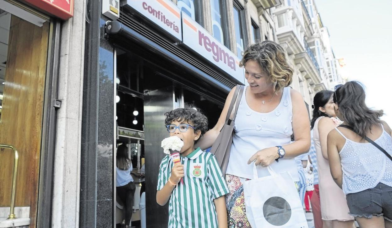 Un niño sale feliz de una heladería de Regma con su helado. 