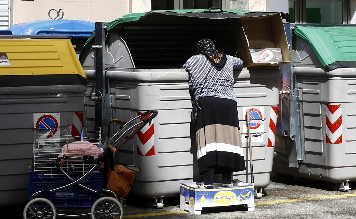 Una mujer rebusca entre los residuos depositados en un contenedor en Torrelavega.