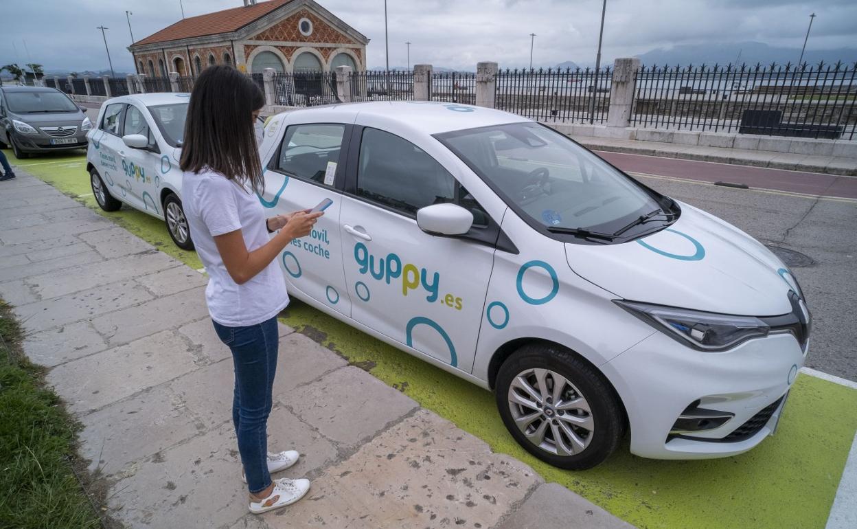 Una joven con su teléfono ante los coches de alquiler aparcados en la zona de Gamazo. 