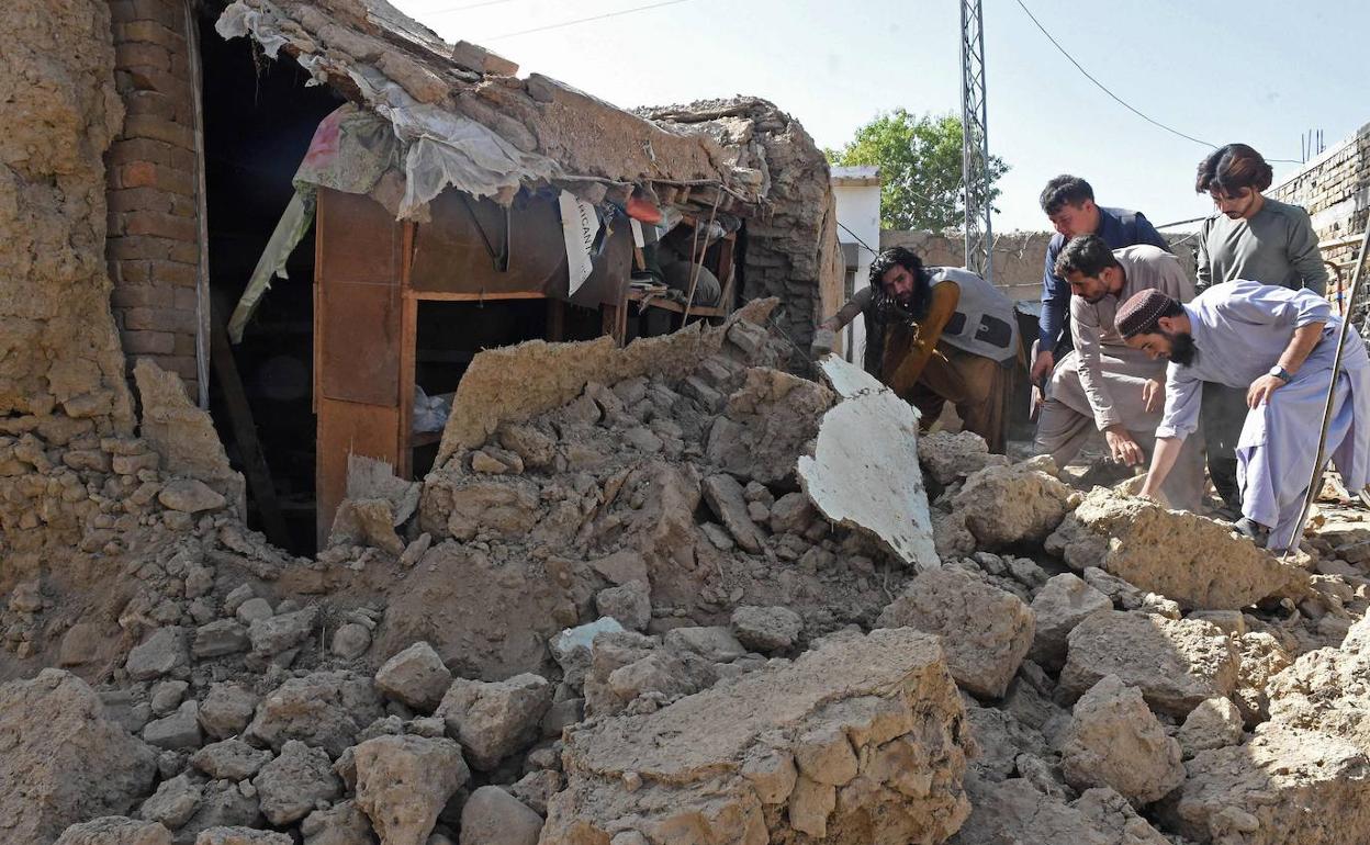 Varios hombres buscan víctimas bajo los escombros de una casa derruida por el terremoto que afectó a Pakistán.