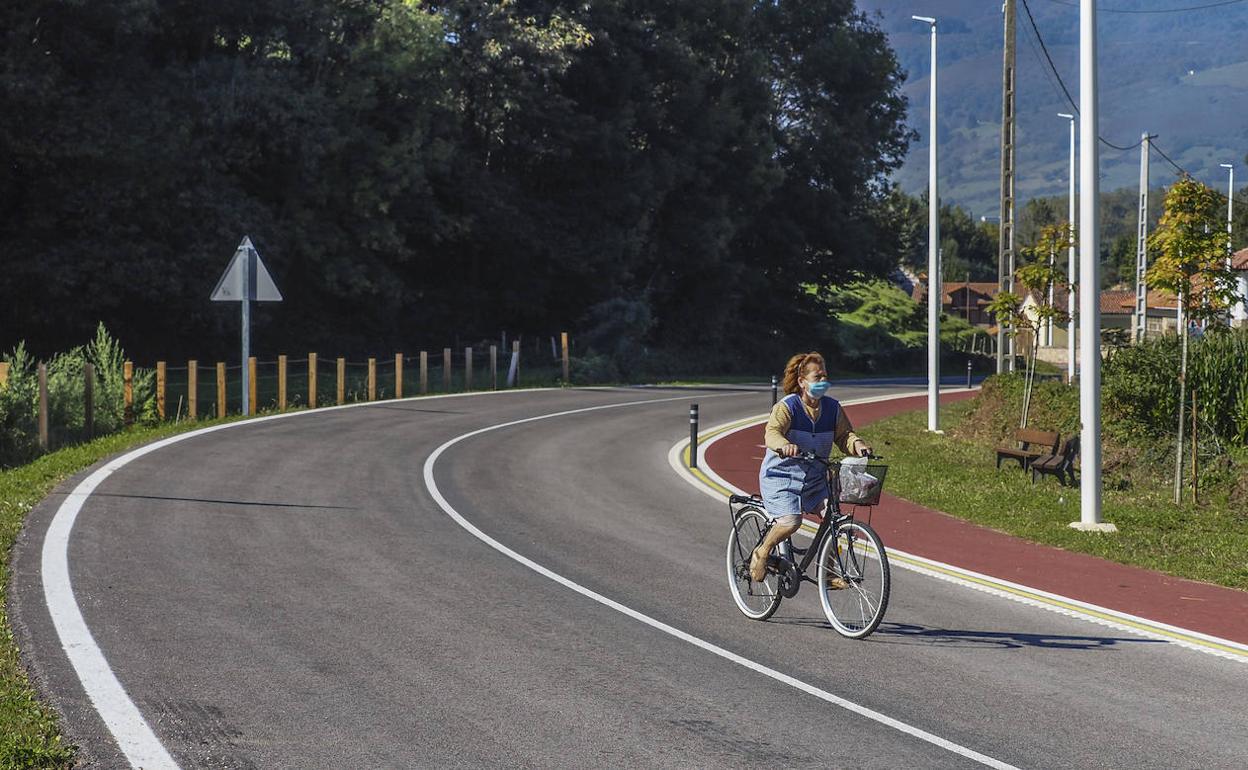 Una mujer circula con su bicicleta por uno de los tramos de la carretera inaugurada ayer.