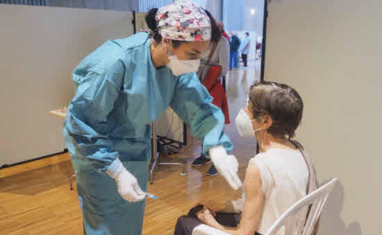 Una sanitaria vacuna a una mujer mayor de 80 años en el Palacio de Exposiciones y Congresos de Santander,