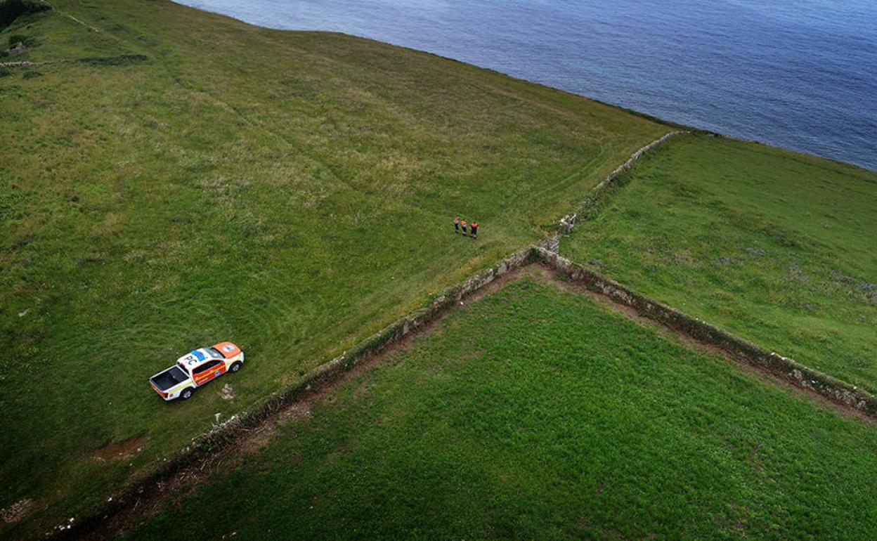 Vehículo de Protección Civil junto a tres operarios en uno de los acantilados de Alfoz de Lloredo. 