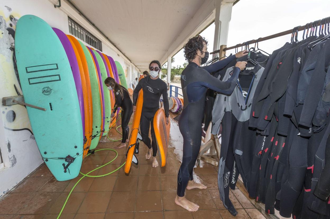 Instructores de una escuela de surf de Santander revisan las tablas y los neoprenos tras una jornada en el mar. 