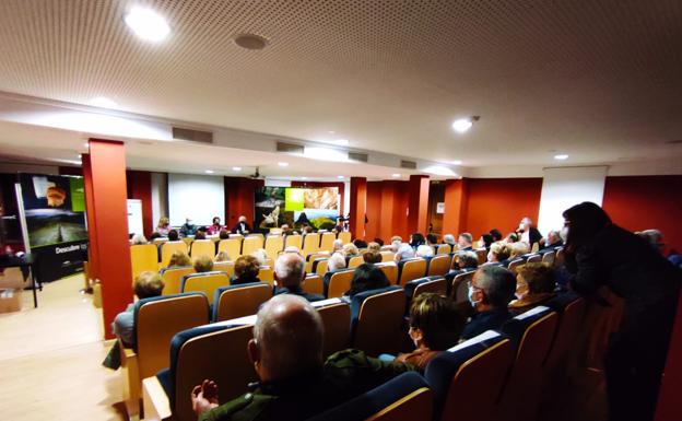 Imagen principal - Varios momentos de la presentación del libro en Villacarriedo, con los ponentes y un aforo completo. 