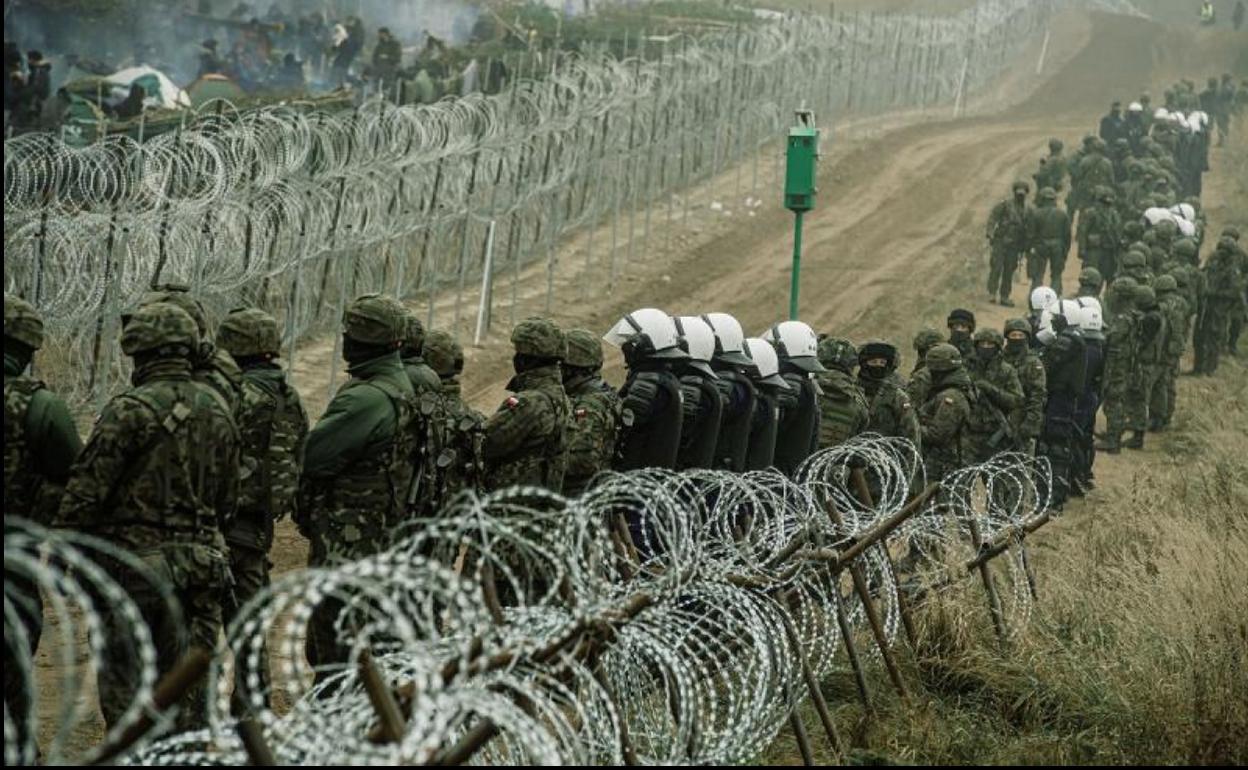 Policías y soldados polacos vigilan el vallado que separa su territorio de Bielorrusia.