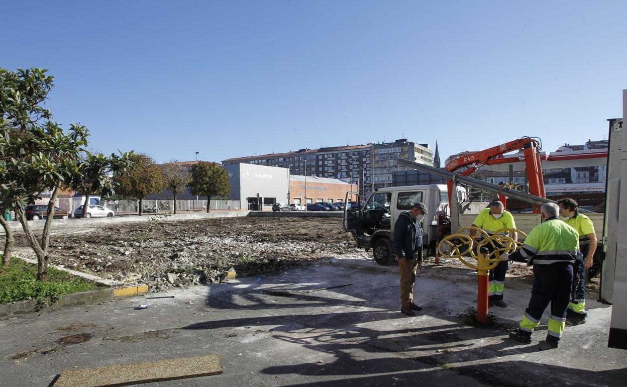 Operarios municipales desmontan los aparatos de ejercicio biosaludable instalados en la parcela. 