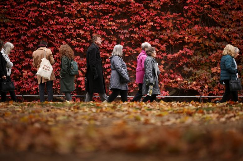 La gente pasa junto a una pared cubierta de follaje que muestra los colores otoñales en Londres, Gran Bretaña, el 4 de noviembre de 2021. 