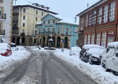 Imagen secundaria 1 - Máquina quitanieves en las aceras de Reinosa. Vista del teatro de la población y vecinos quitando nieve en Villaescusa.