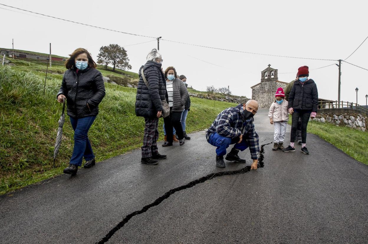 Un grupo de afectados muestra una grieta en la calzada a pocos metros de la ermita de La Montaña. 