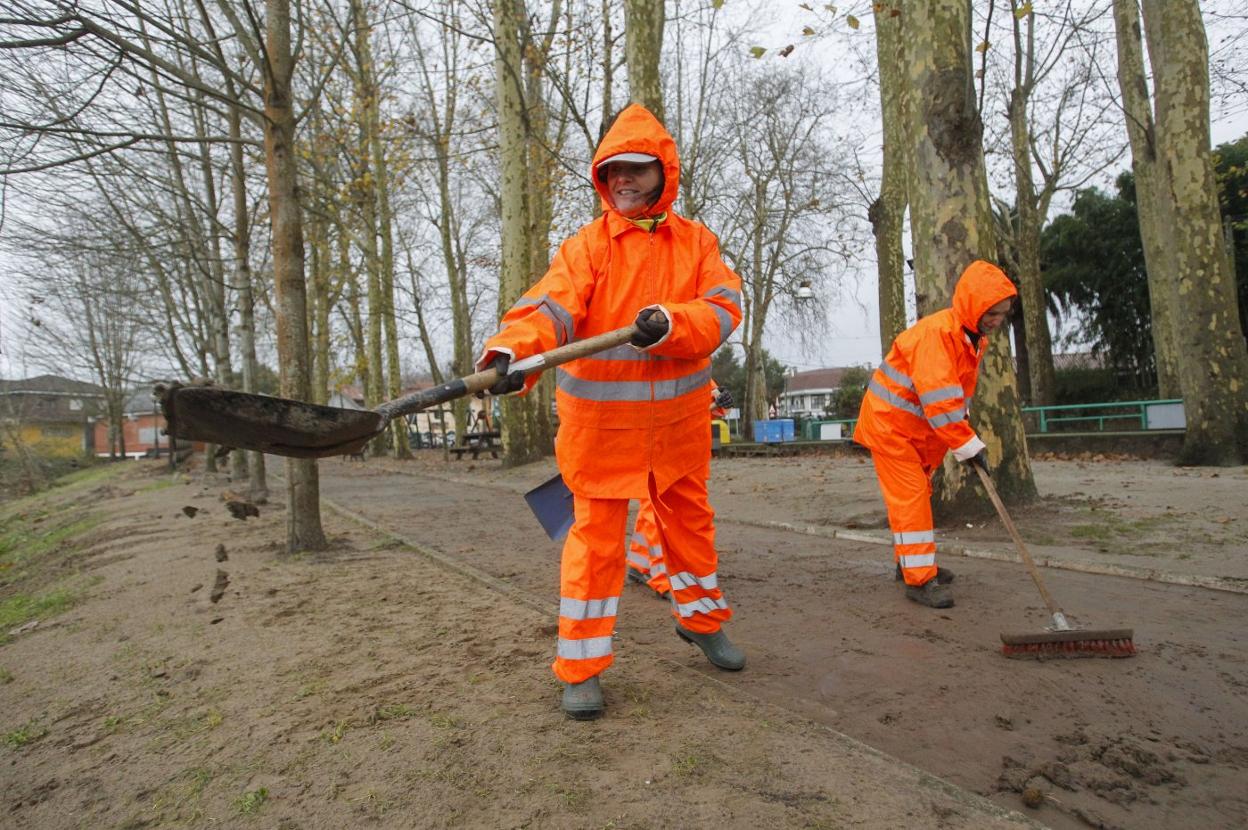 Oruña. Los operarios municipales limpian el paseo junto al río, que quedó cubierto por una espesa capa de barro tras la inundación. 