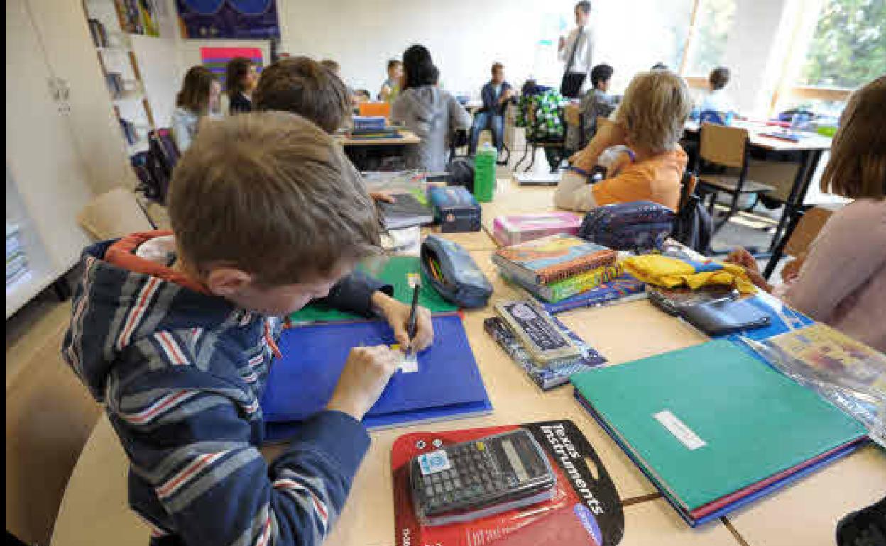 Niños de enseñanza primaria trabajan en su pupitre, en el aula de una escuela pública.