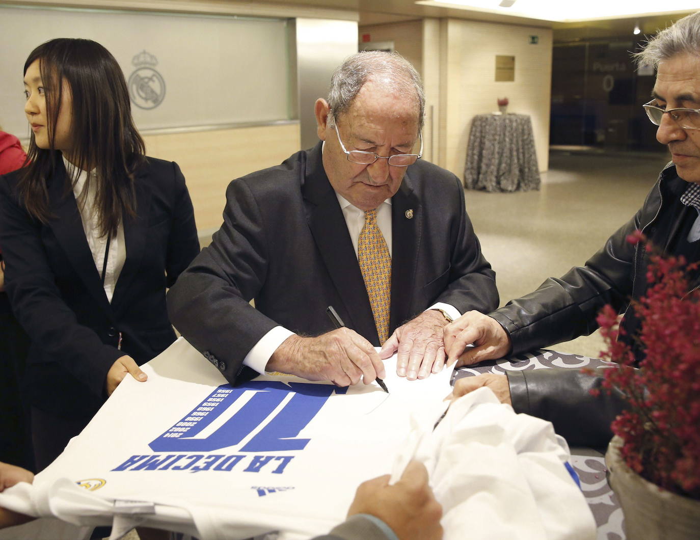 Paco Gento firma una camiseta durante su asistencia al foro Luis de Carlos sobre 'Las 10 Copas de Europa', organizado por la Fundación Real Madrid, en el estadio Santiago Bernabéu. 