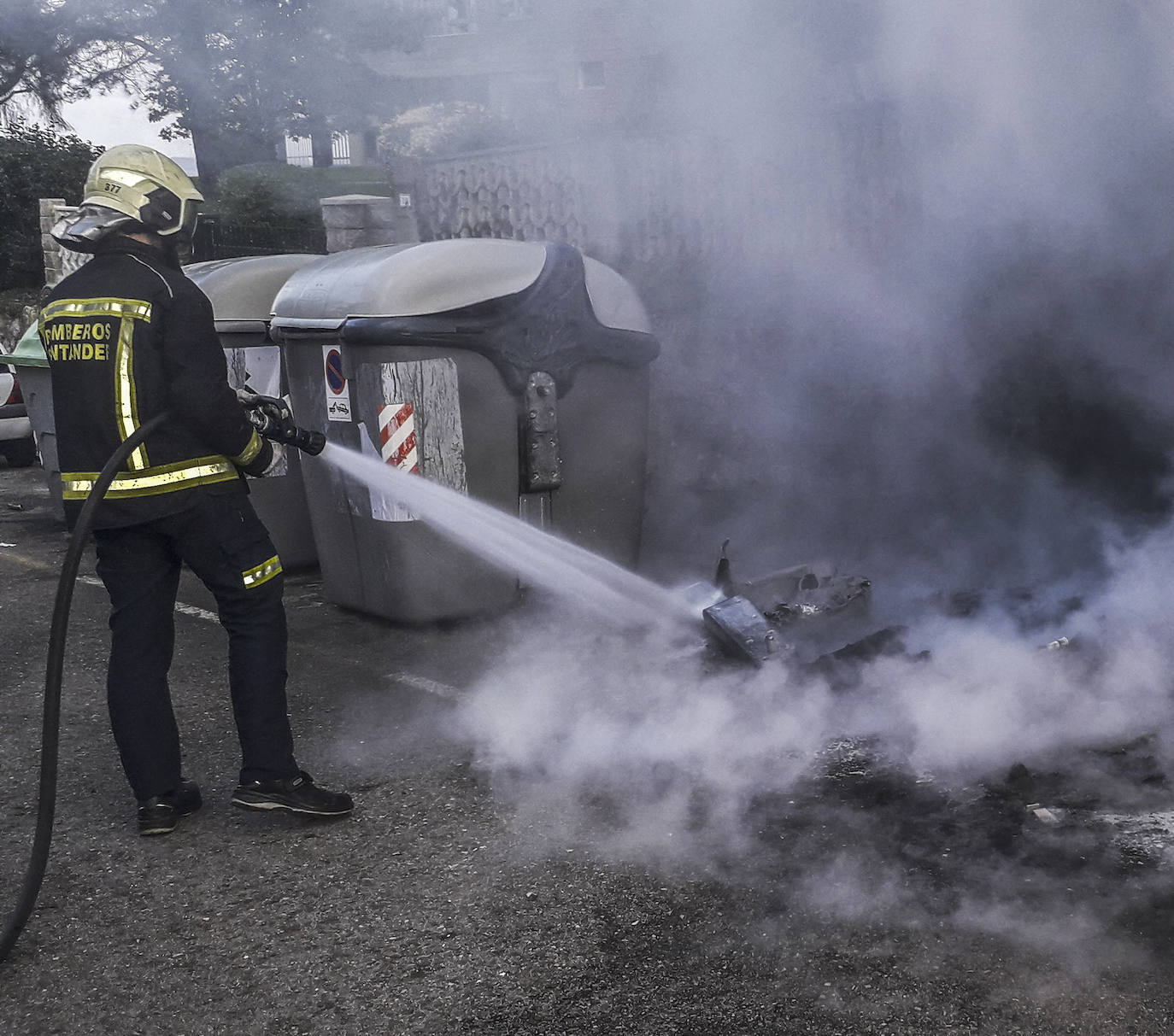 Un bombero apaga un fuego en contenedores quemados