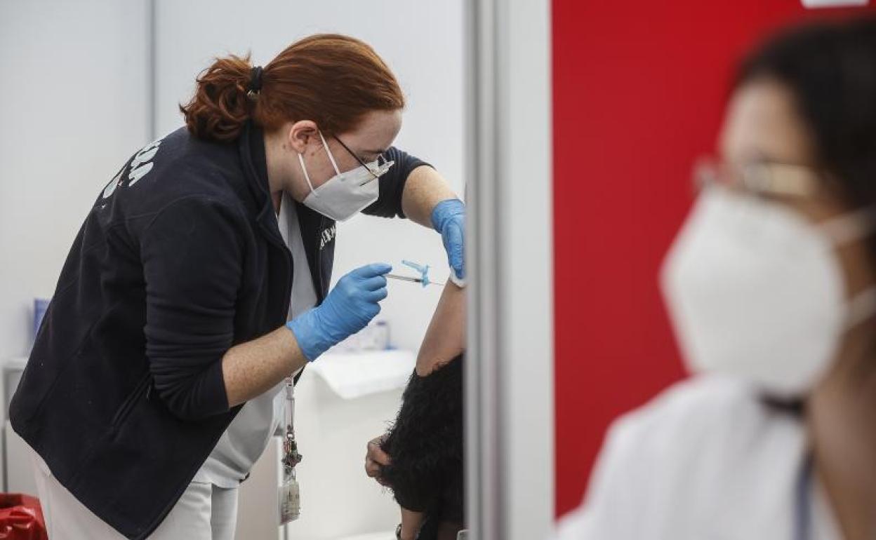 Una sanitaria vacuna a una persona con la tercera dosis de la vacuna de Moderna en la Ciudad de las Artes y las Ciencias de Valencia.