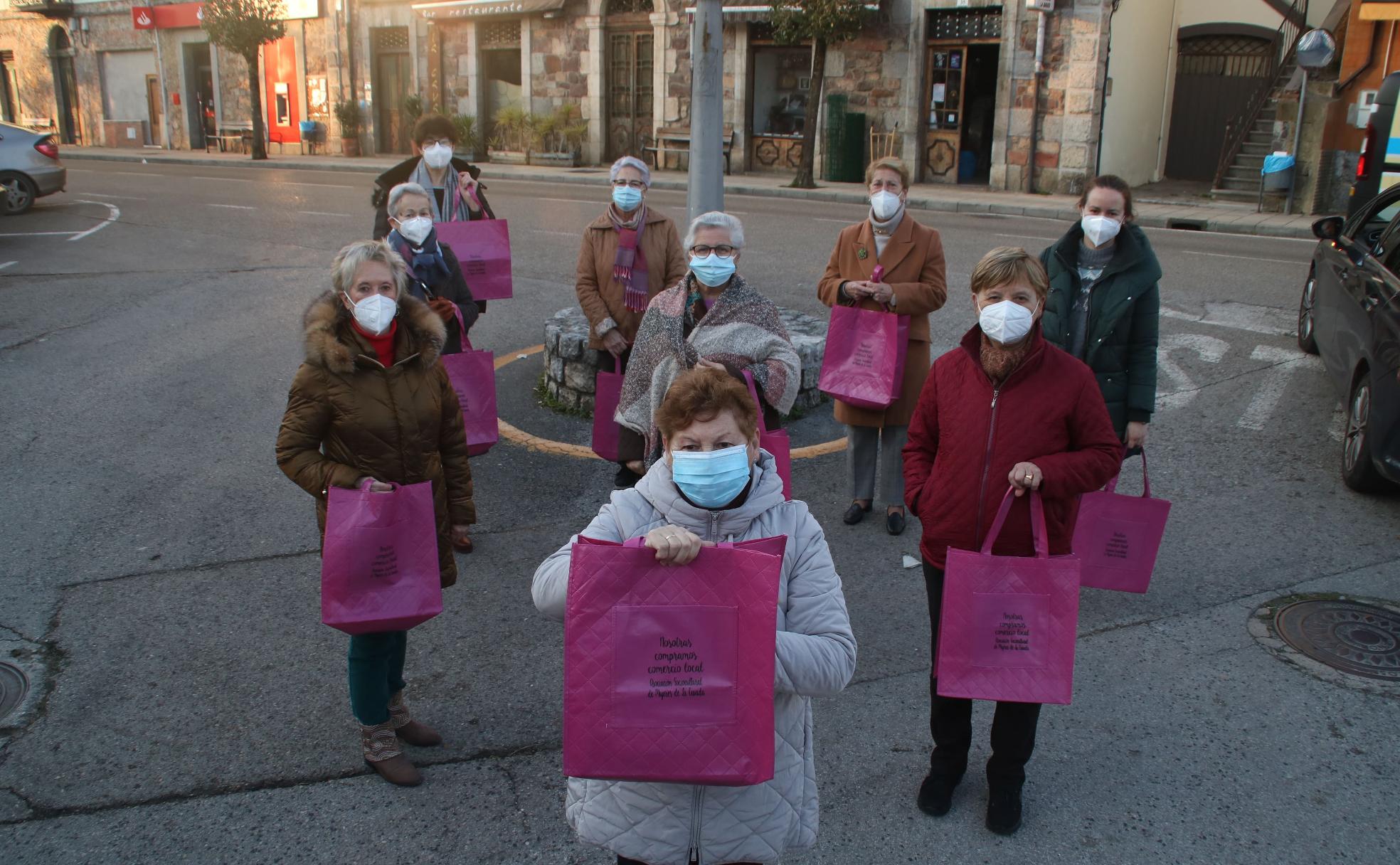 Un grupo de mujeres porta las bolsas que han repartido para apoyar el comercio local 