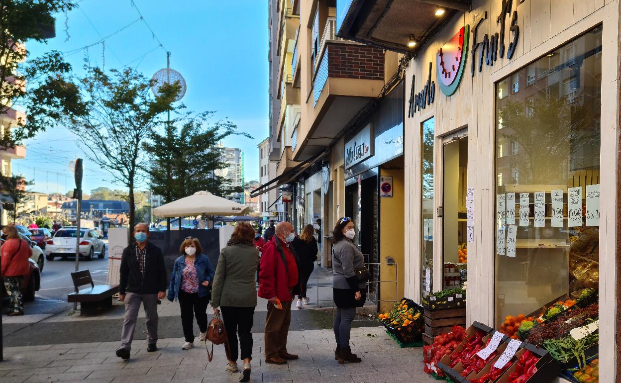 Vecinos se detienen ante un escaparate del casco urbano de Maliaño-Muriedas, en una imagen tomada durante la pandemia.