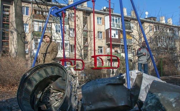 Un hombre y una mujer están de pie junto a fragmentos de equipo militar en la calle tras un ataque ruso en Kharkiv en Ucrania, el 24 de febrero de 2022.