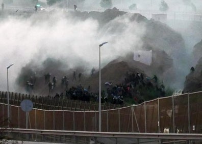 Imagen secundaria 1 - Arriba, algunos de los inmigrantes que han saltado la valla este jueves. Abajo, imagen de la valla y un agente con herramientas empleadas para escalar. 