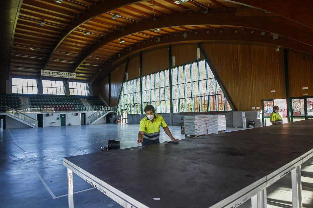 Operarios colocan un escenario en el pabellón multiusos Sergio García de La Lechera.