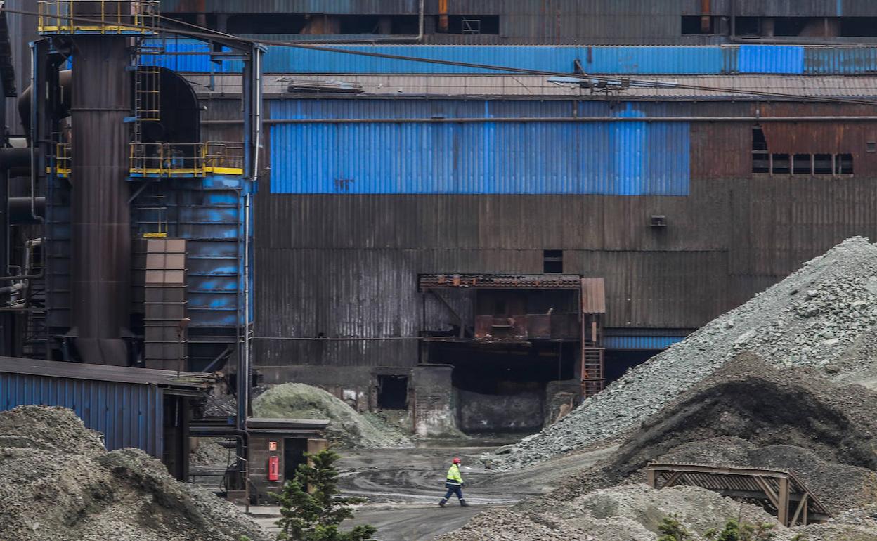 Un trabajador camina ayer en solitario por el complejo de Ferroatlántica en Boo de Guarnizo, con la planta ya parada