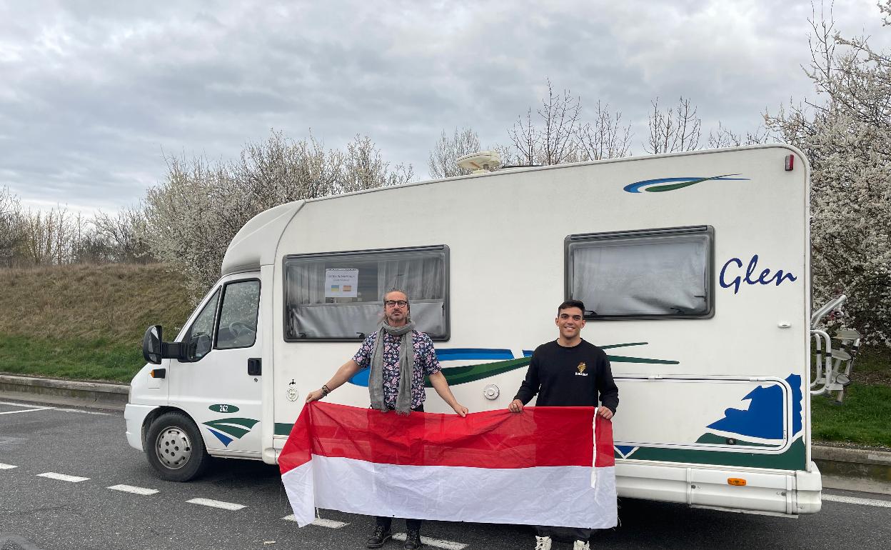 Los santoñeses, Emilio Muela y Rafael Arisqueta, con la bandera de Santoña junto a la caravana repleta de material. 