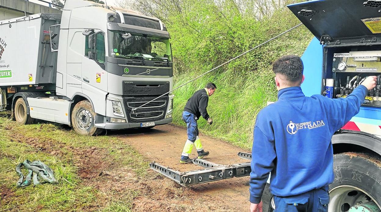 Los operarios de la grúa, durante las labores para sacar el camión polaco de la zona de la senda verde en la que quedó atascado. 