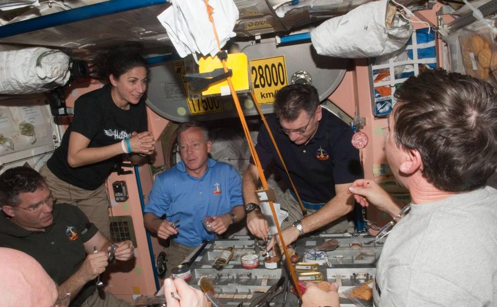 Un grupo de astronautas come en la Estación Espacial Internacional.