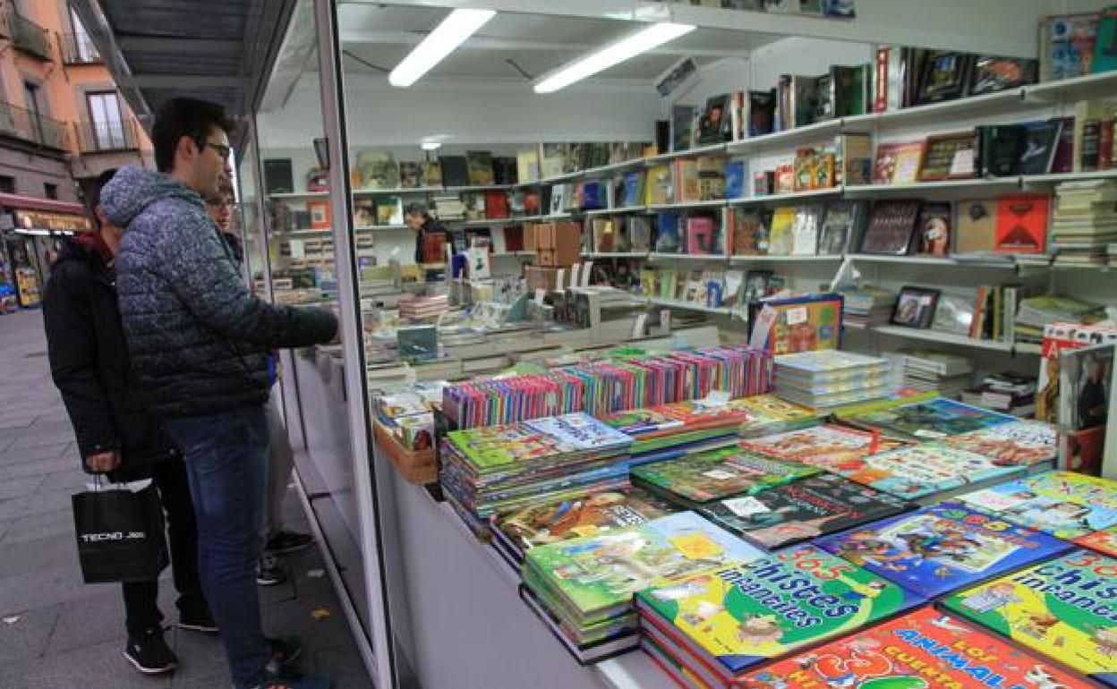 Un grupo de jóvenes observan los libros de un puesto en una feria del libro. 