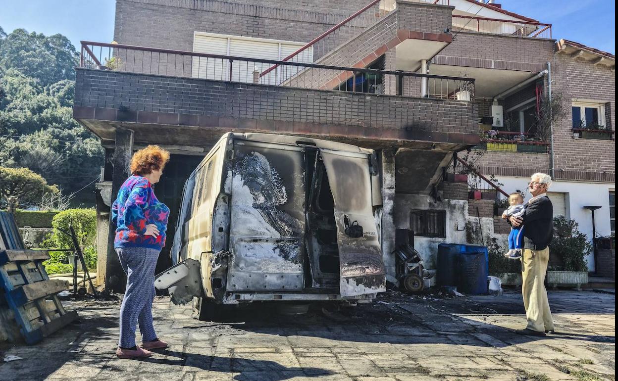 María Ángeles Cuerno y José Antonio Fernández (con su nieto en brazos) contemplan las secuelas del fuego en su casa, el miércoles, en Camargo.