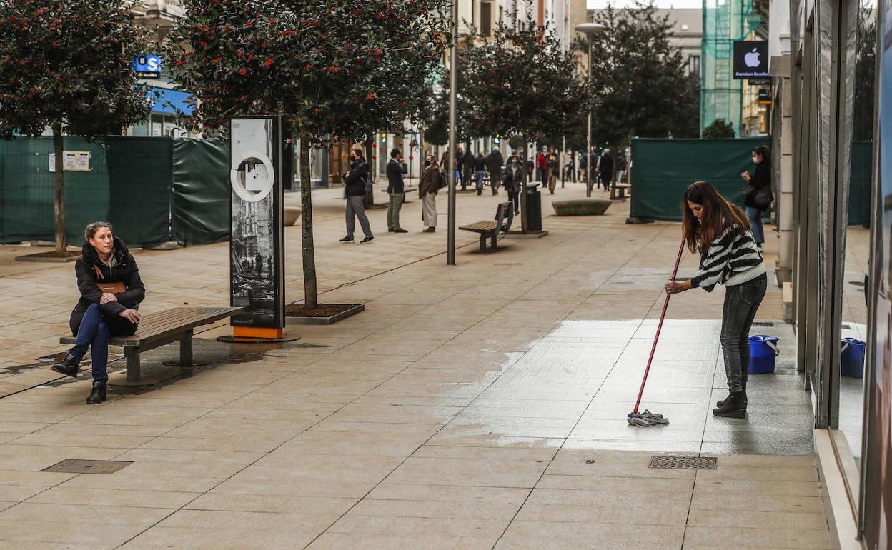 La responsable de un comercio limpia el entorno de su tienda en la calle Juan de Herrera de Santander.