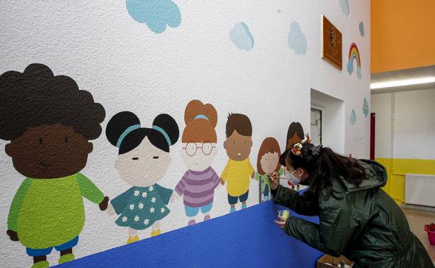 Una pintora decora el interior del colegio José María Pereda. 