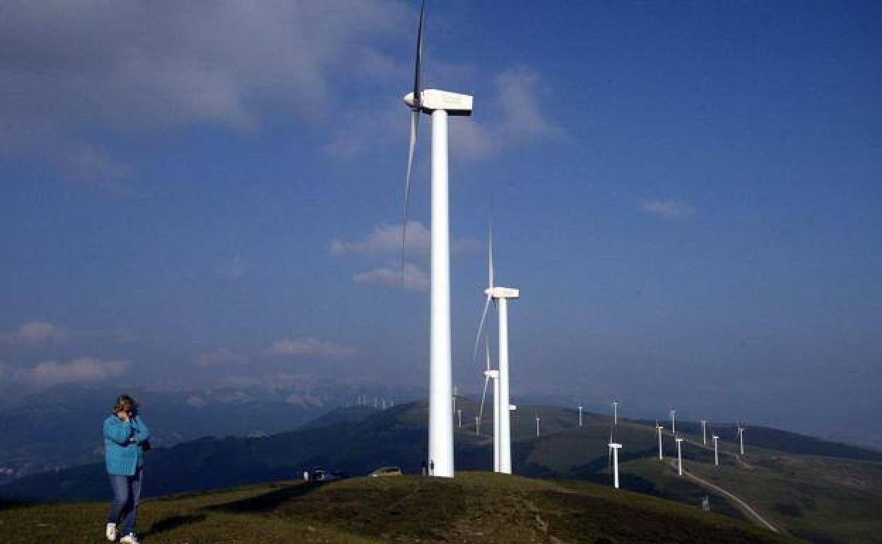 Una mujer habla por teléfono en un monte repleto de aerogeneradores.