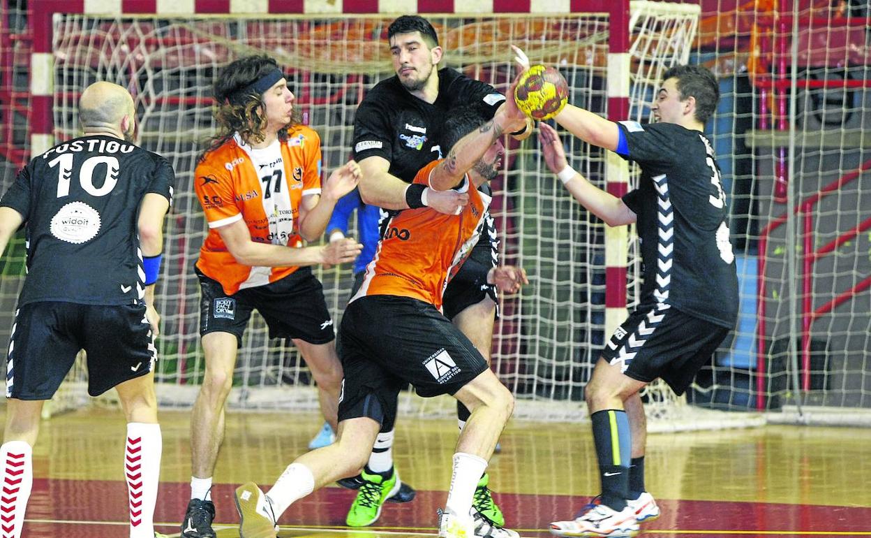 Nico Colunga –77–, central del Torrelavega, junto a Diego Muñiz, pivote del Sinfín, que agarra a un rival naranja durante el derbi en el Trueba. 