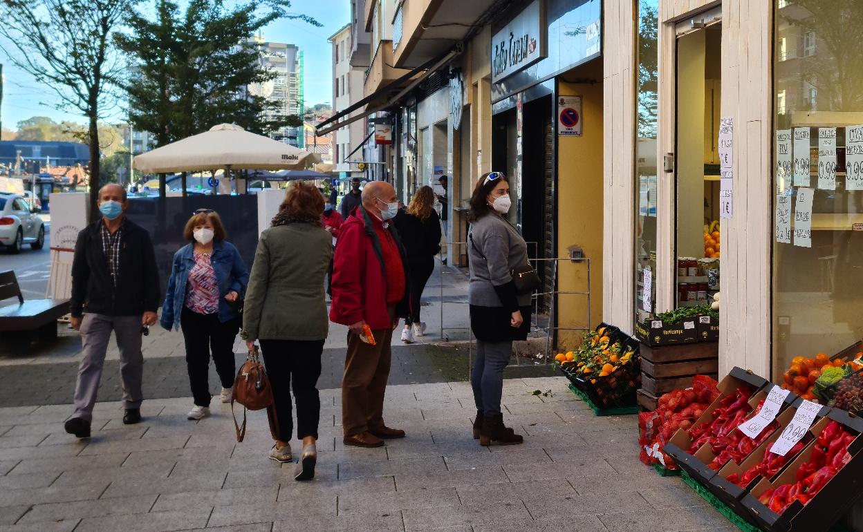 Vecinos se detienen ante un escaparate del casco urbano de Maliaño-Muriedas (Camargo), en una imagen tomada durante la pandemia.