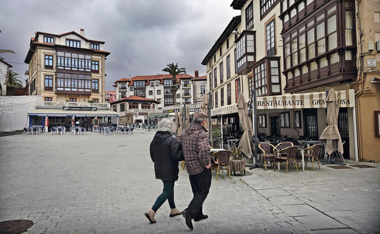 Una pareja pasea por la plaza del Corro de Comillas. 