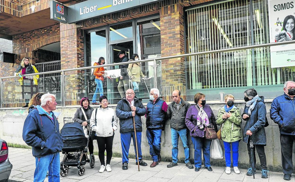 Un grupo de vecinos de Somo se manifestó ayer frente a la sucursal de Unicaja, que tiene previsto cerrar su servicio al público.