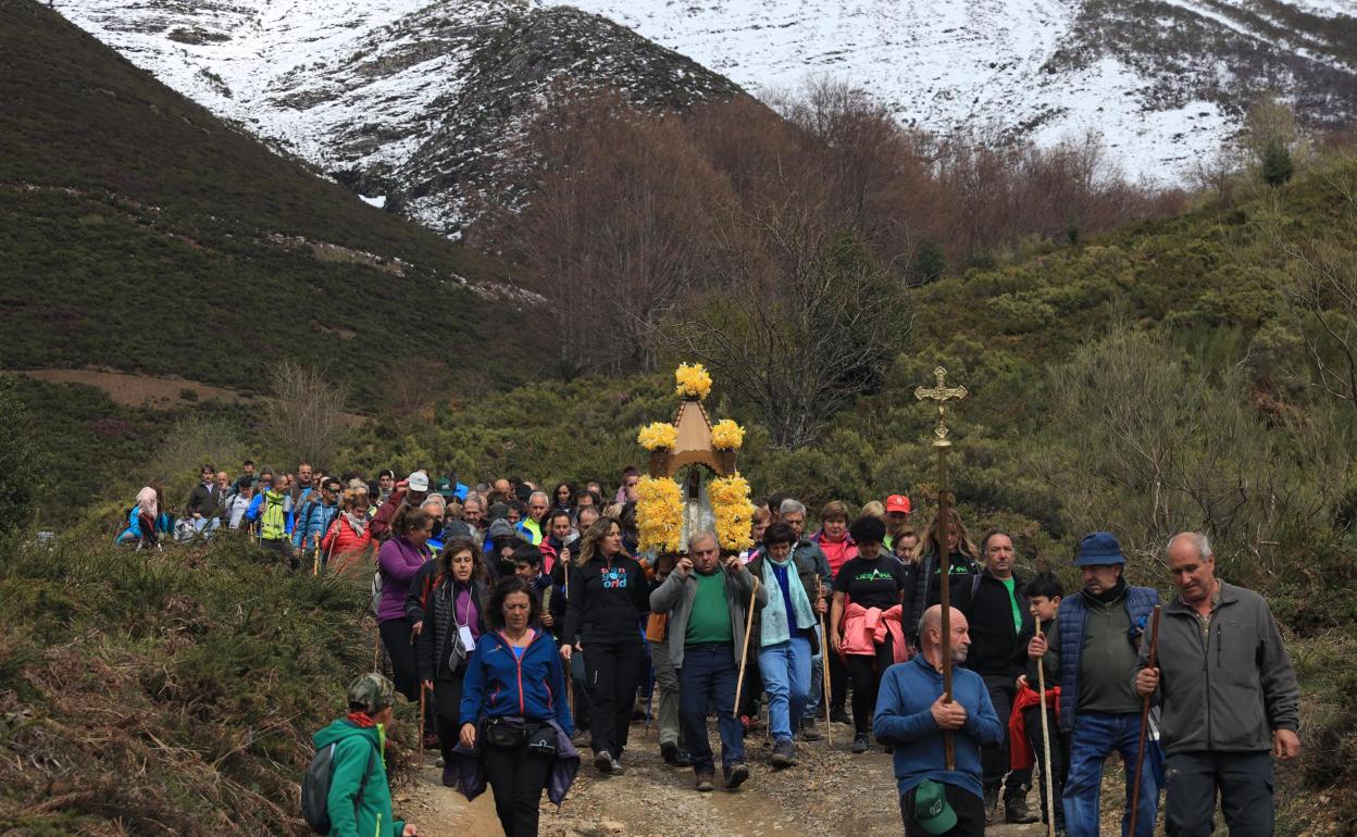 Un devoto lleva las andas de la Virgen de la Luz camino de Somaniezo, con el fondo de Peña Sagra nevada 