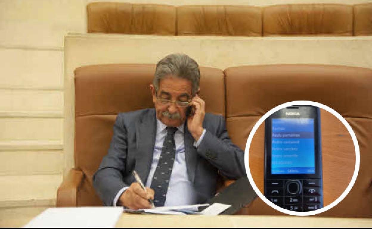 El presidente del Gobierno de Cantabria habla por teléfono en el Parlamento en una foto de archivo. A la derecha, el Nokia 301.1 de Revilla.