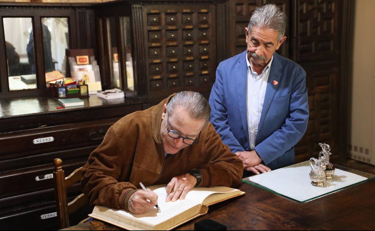 El embajador firma en el libro de honor del monasterio junto al presidente regional 