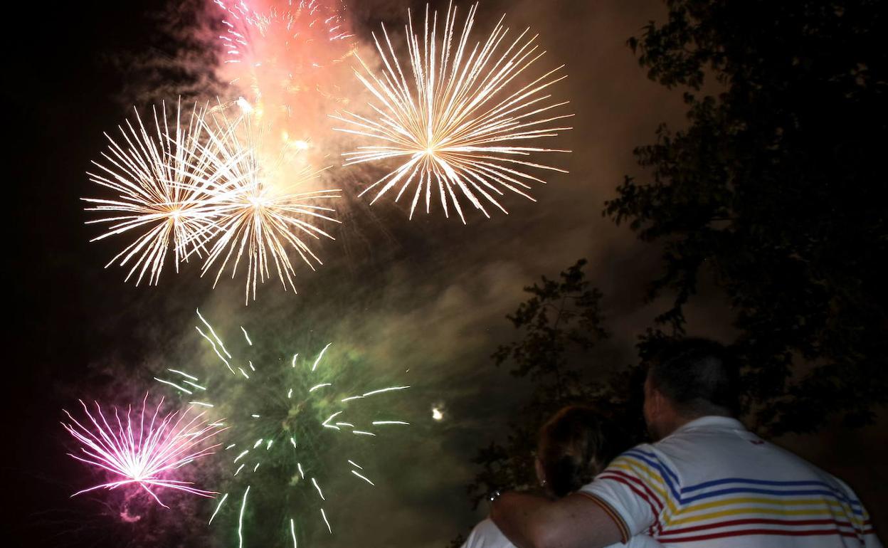 Dos personas contemplan unos fuegos artificiales.
