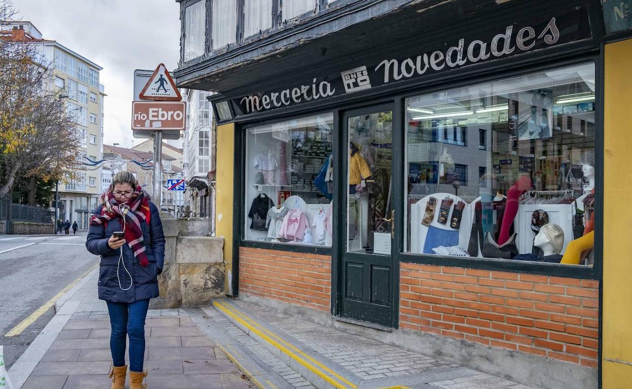 Una mujer pasea por una calle comercial de Reinosa. 