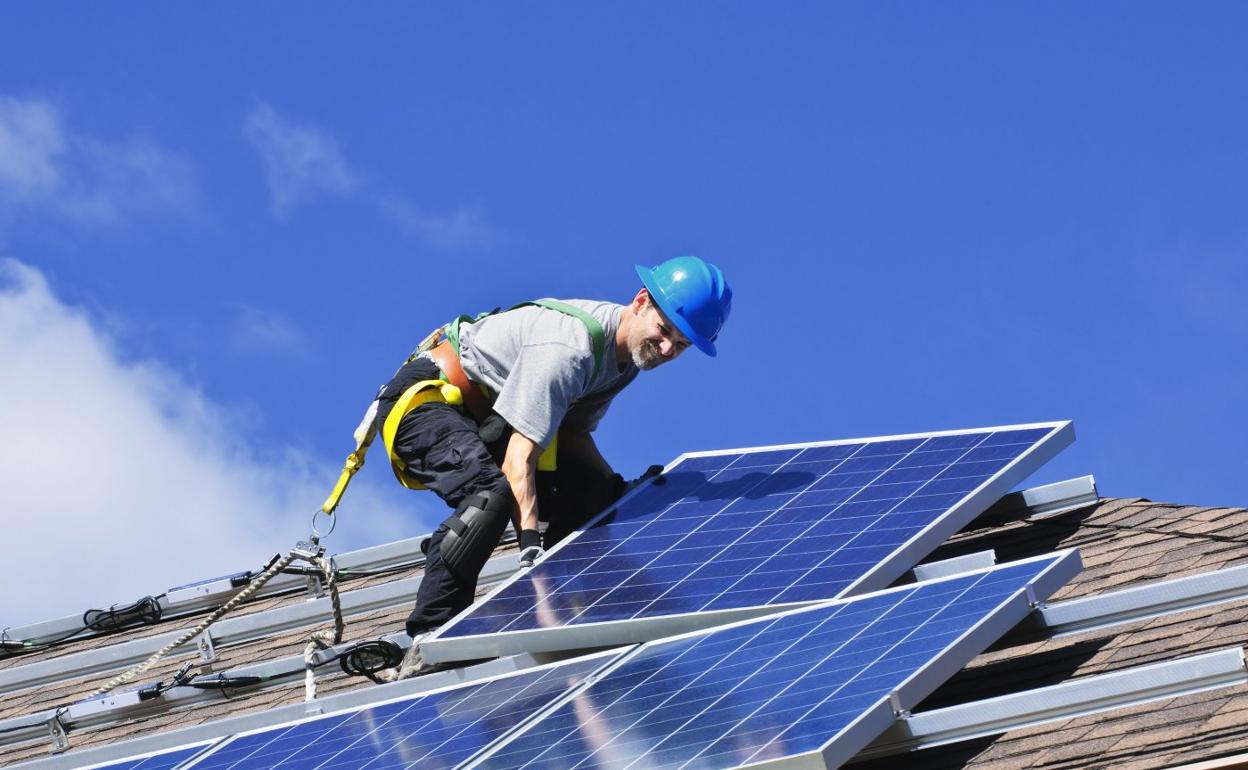 Un operario instala paneles fotovoltaicos en el tejado de una vivienda. 