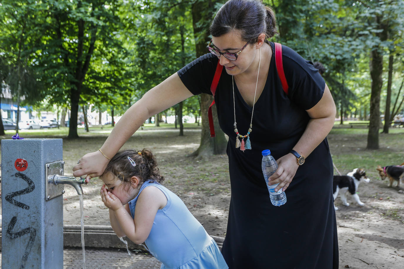 Una madre y su hija beben agua en un parque de Torrelavega.