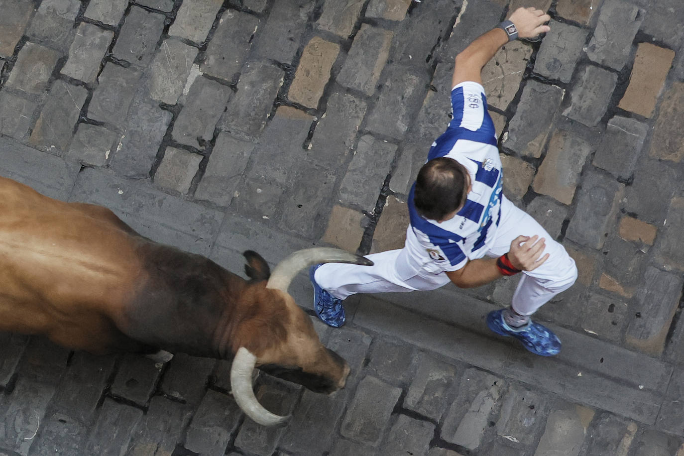 Un mozo ante uno de los toros de la ganadería gaditana de Cebada Gago en la calle de la Estafeta durante el quinto encierro de los Sanfermines. 