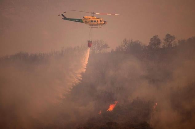 Un helicóptero de los servicios de emergencias intenta apagar el fuego en Alhaurín de la Torre