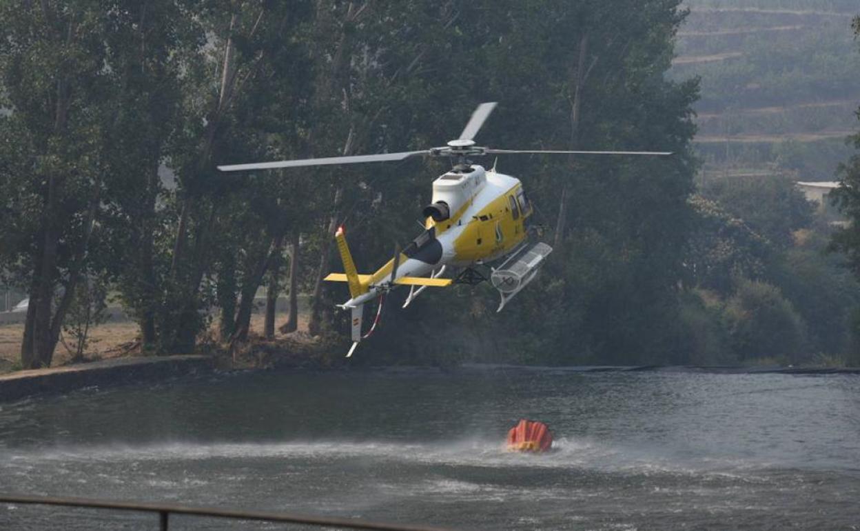 Un helicóptero se abastece de agua para lanzar sobre las llamas del incendio de Monfragüe. 